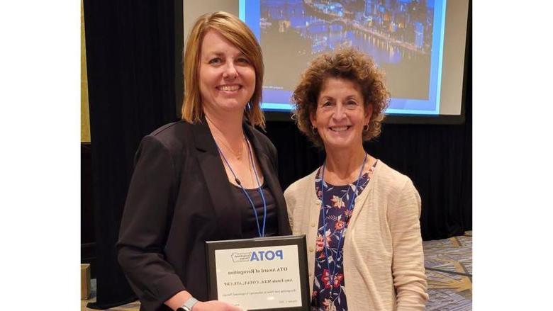 在2022年POTA会议上，LuAnn Delbrugge和Amy Fatula拿着她的OTA认可奖.