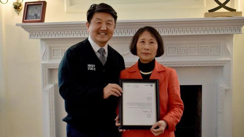 Penn State 杜波依斯 chancellor and chief academic officer Jungwoo Ryoo, 正确的, presents Pingjuan Werner with a framed copy of the letter certifying her as a distinguished professor, the highest professorial distinction at the University